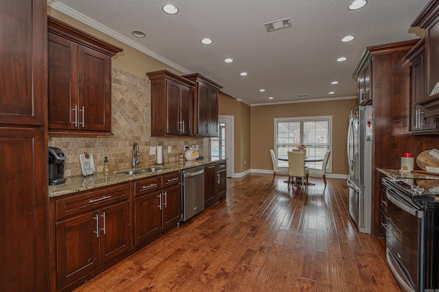 kitchen featuring hardwood / wood-style floors, appliances with stainless steel finishes, light stone countertops, ornamental molding, and sink