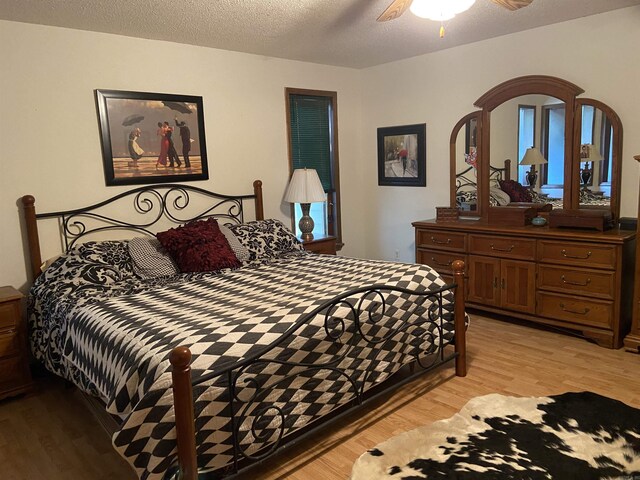 bedroom with a textured ceiling, ceiling fan, and light wood-type flooring