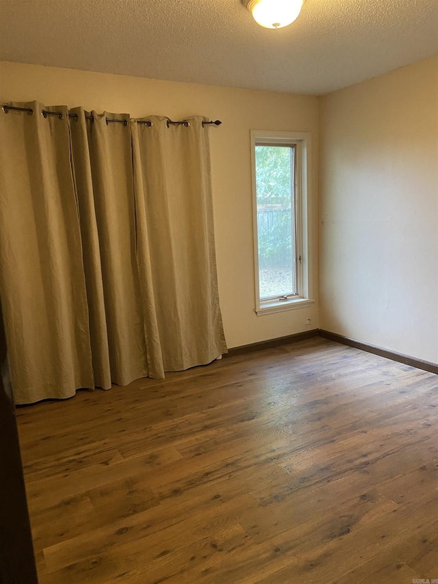 spare room featuring dark hardwood / wood-style floors and a textured ceiling