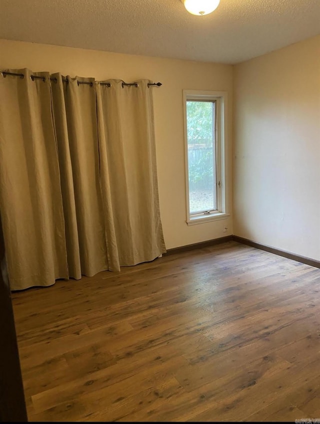 empty room featuring wood-type flooring and a textured ceiling