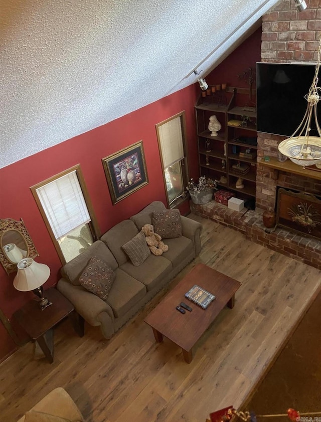 living room with a textured ceiling, hardwood / wood-style floors, and vaulted ceiling