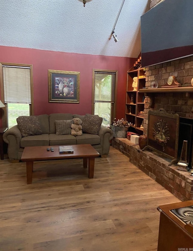 living room with vaulted ceiling, a fireplace, a textured ceiling, and plenty of natural light