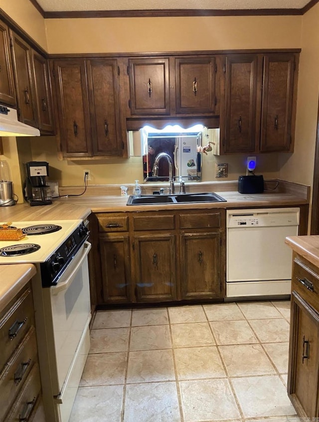 kitchen with light tile patterned flooring, dark brown cabinets, sink, and white appliances