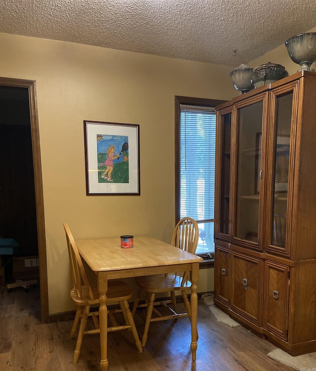 dining room with wood-type flooring and a textured ceiling