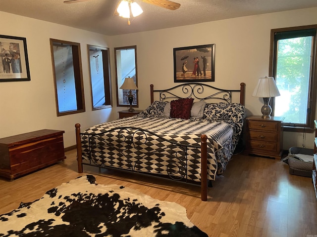 bedroom with ceiling fan, a textured ceiling, and wood-type flooring