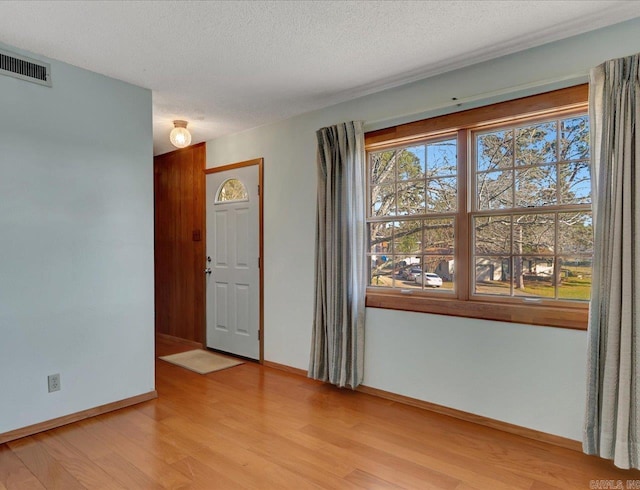 spare room with a textured ceiling and light wood-type flooring