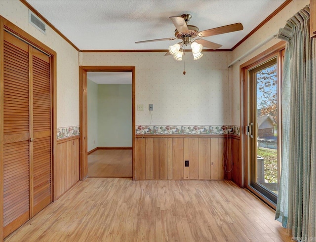 interior space featuring ornamental molding, ceiling fan, light hardwood / wood-style floors, and a textured ceiling