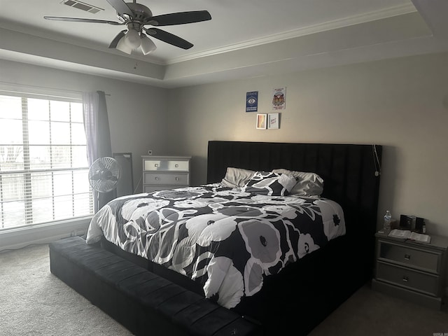 carpeted bedroom featuring multiple windows, ceiling fan, a tray ceiling, and crown molding