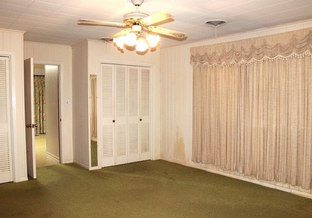 interior space with ceiling fan, crown molding, and dark colored carpet