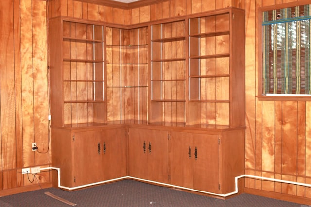 interior details featuring crown molding, wood walls, and carpet flooring