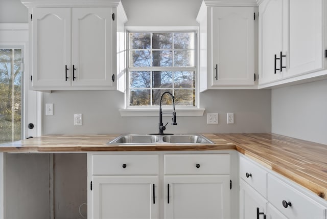 kitchen with sink, butcher block countertops, and white cabinetry