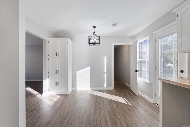 unfurnished dining area featuring a chandelier and wood-type flooring