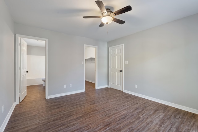 unfurnished bedroom featuring dark hardwood / wood-style flooring, ceiling fan, ensuite bath, and a spacious closet