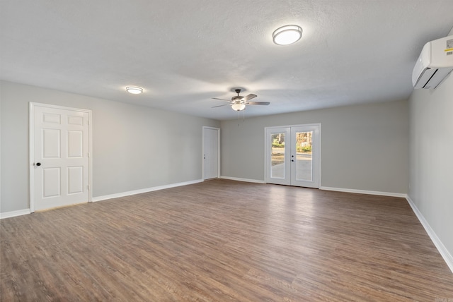 spare room featuring dark wood-type flooring, ceiling fan, french doors, and a wall mounted air conditioner