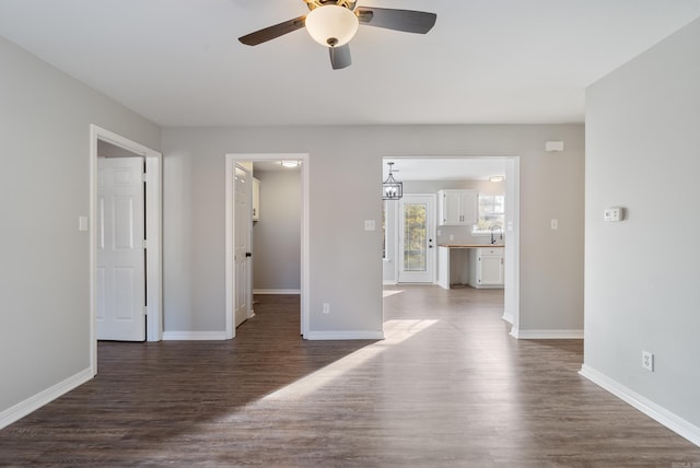 unfurnished room featuring ceiling fan with notable chandelier and dark wood-type flooring