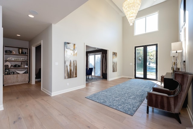 entryway with a high ceiling, french doors, an inviting chandelier, and light hardwood / wood-style floors