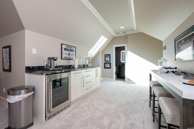 kitchen with sink, white cabinetry, lofted ceiling, light carpet, and wine cooler