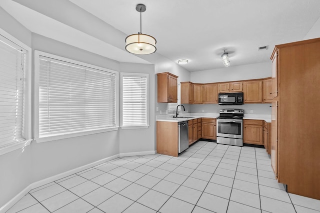 kitchen featuring hanging light fixtures, light tile patterned floors, sink, and appliances with stainless steel finishes