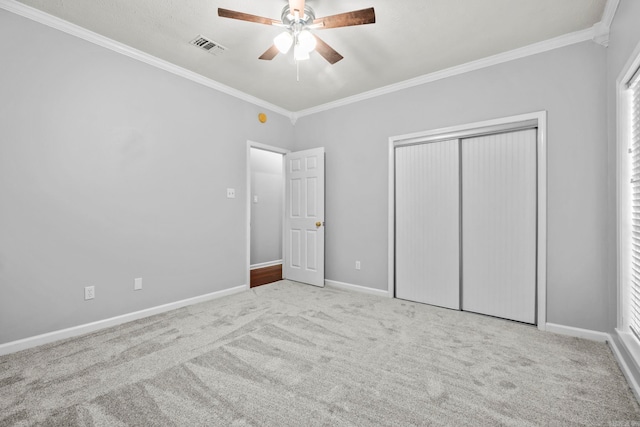 unfurnished bedroom featuring ornamental molding, light carpet, ceiling fan, and a closet