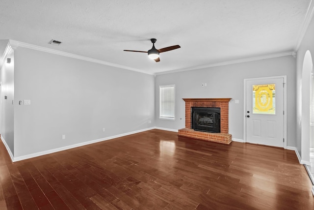 unfurnished living room with crown molding, ceiling fan, dark hardwood / wood-style floors, a textured ceiling, and a brick fireplace