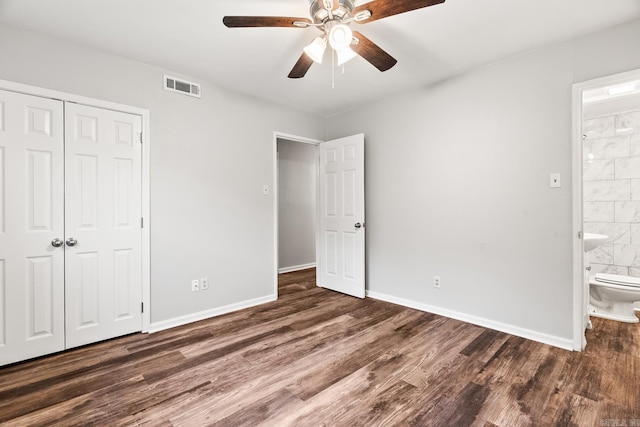 unfurnished bedroom with ensuite bath, a closet, ceiling fan, and dark hardwood / wood-style floors