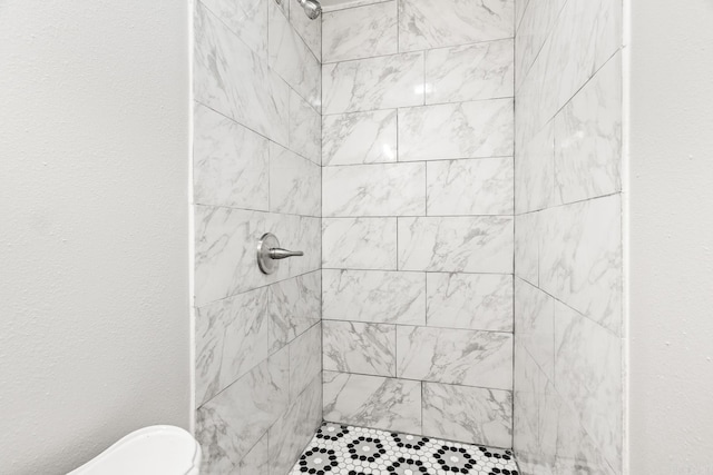 bathroom featuring a tile shower and toilet