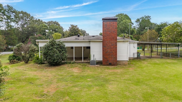 rear view of property with cooling unit, a yard, and a carport