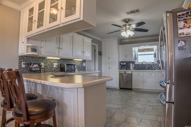 kitchen featuring a breakfast bar area, appliances with stainless steel finishes, kitchen peninsula, sink, and white cabinetry