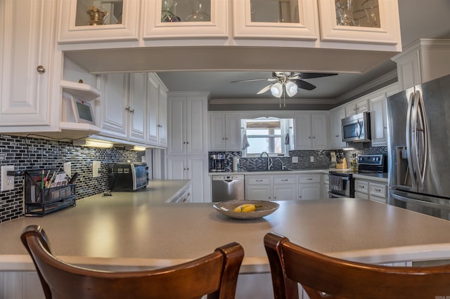 kitchen featuring stainless steel appliances, sink, white cabinets, ceiling fan, and crown molding