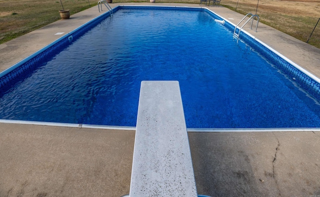 view of pool featuring a diving board and a yard