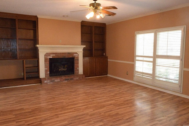 unfurnished living room with hardwood / wood-style floors, a brick fireplace, crown molding, built in features, and ceiling fan