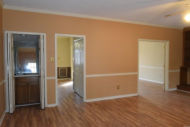 empty room with dark hardwood / wood-style flooring, a textured ceiling, ceiling fan, and crown molding