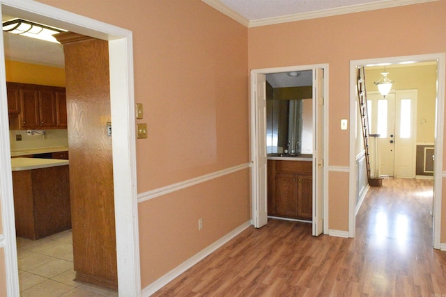 corridor with light hardwood / wood-style floors and crown molding