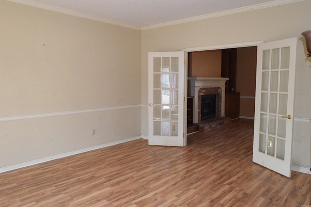 unfurnished living room with a brick fireplace, french doors, ornamental molding, and hardwood / wood-style floors