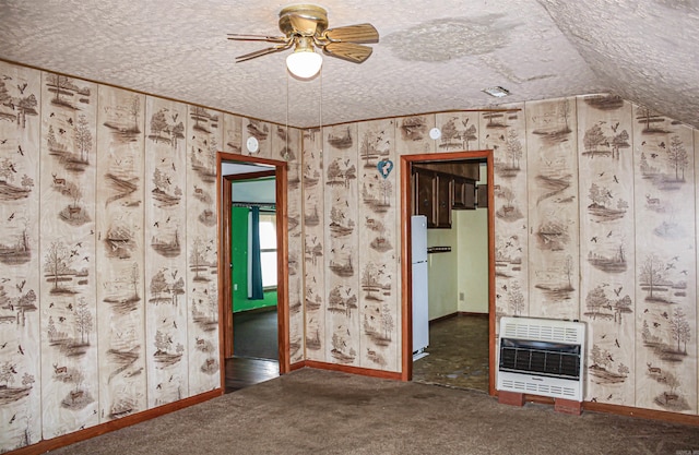 unfurnished room featuring a textured ceiling, ceiling fan, heating unit, and dark colored carpet