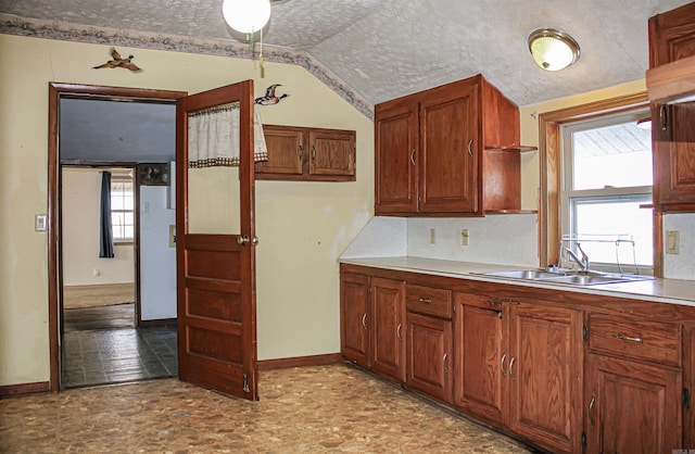 kitchen featuring vaulted ceiling, sink, and a textured ceiling