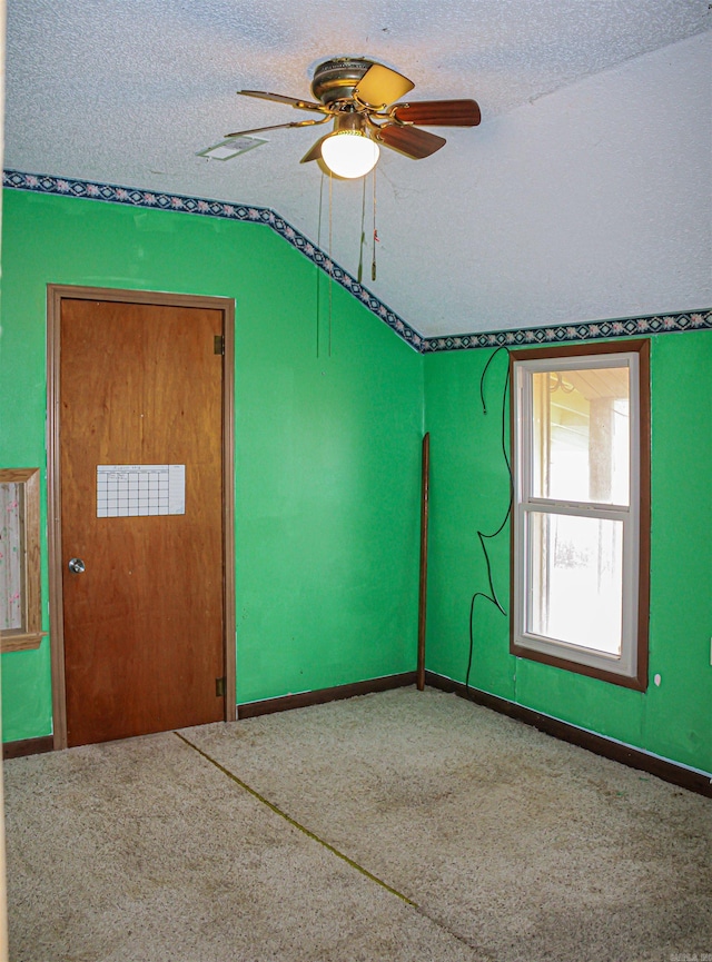 carpeted spare room featuring ceiling fan and a textured ceiling