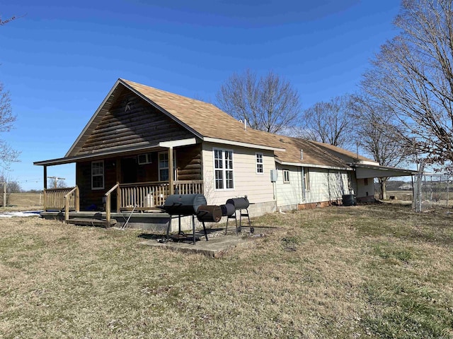 rear view of property featuring a lawn and covered porch