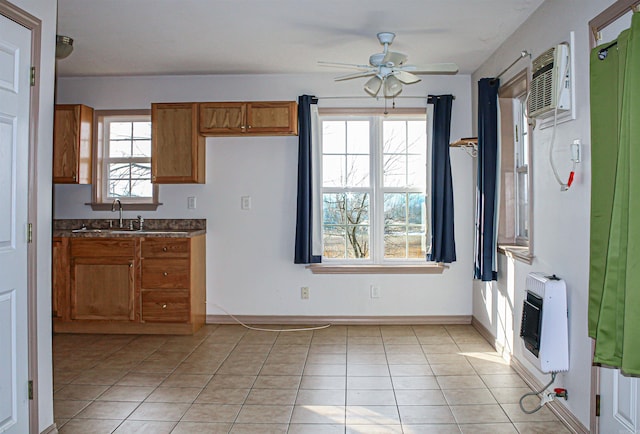 kitchen featuring ceiling fan, a wall mounted air conditioner, light tile patterned flooring, heating unit, and sink