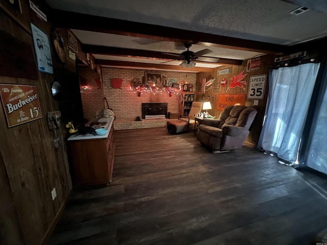 living room featuring wood walls, ceiling fan, brick wall, a fireplace, and beam ceiling