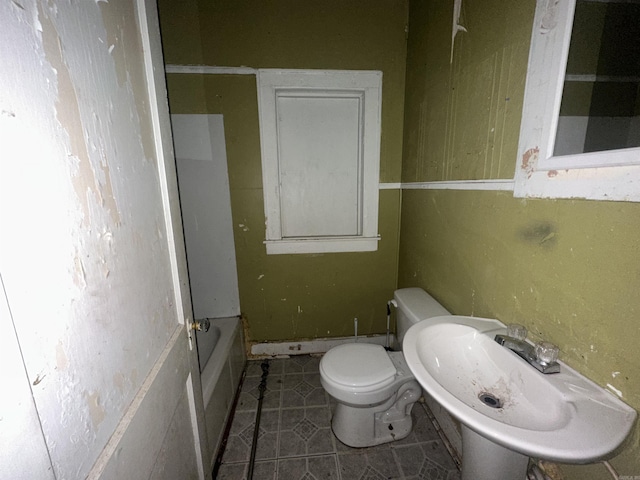 bathroom featuring toilet, tile patterned flooring, sink, and a bathing tub