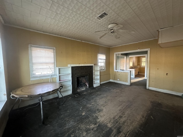 unfurnished living room featuring a brick fireplace, ceiling fan, crown molding, and a wealth of natural light