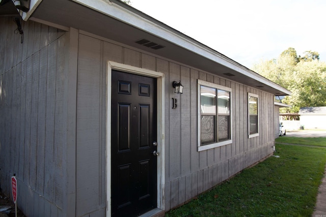 view of exterior entry with a yard