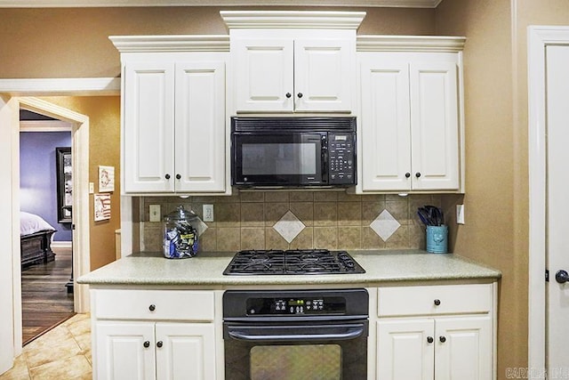 kitchen with white cabinets, black appliances, and tasteful backsplash