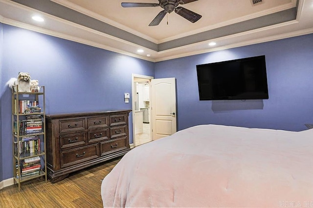 bedroom featuring crown molding, dark wood-type flooring, ceiling fan, and a tray ceiling