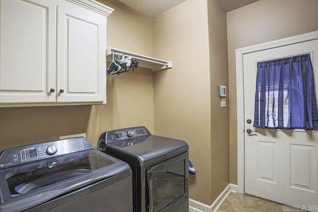 laundry area with washing machine and dryer, light tile patterned floors, and cabinets