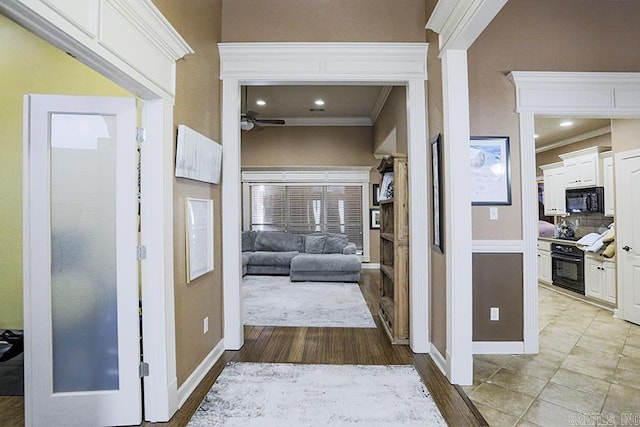 hallway with light wood-type flooring and crown molding