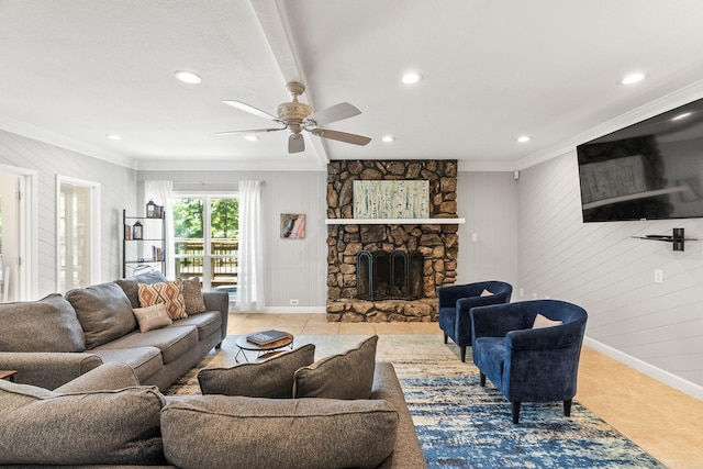 tiled living room with ornamental molding, ceiling fan, wooden walls, and a stone fireplace