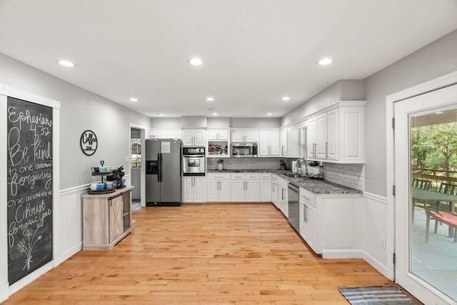 kitchen featuring decorative backsplash, white cabinetry, light hardwood / wood-style flooring, and appliances with stainless steel finishes