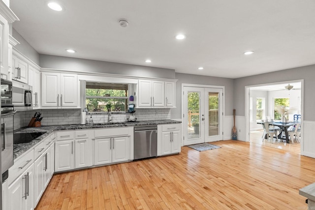 kitchen with stainless steel appliances, dark stone countertops, white cabinets, and sink